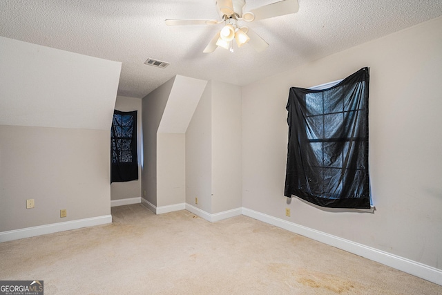 bonus room featuring light carpet, a textured ceiling, and ceiling fan