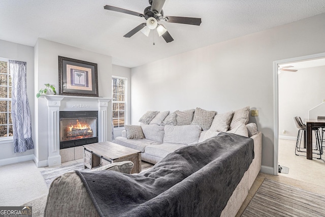 living room with a textured ceiling, ceiling fan, and light carpet