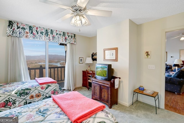 carpeted bedroom with access to exterior, a textured ceiling, and ceiling fan