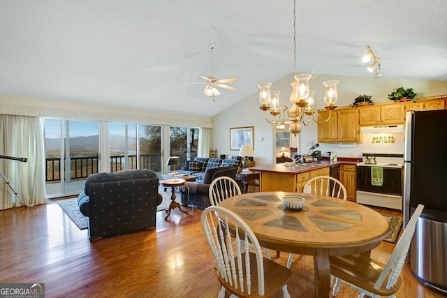 dining space featuring a textured ceiling, ceiling fan with notable chandelier, sink, light hardwood / wood-style floors, and lofted ceiling