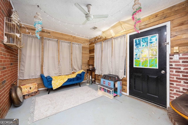 interior space with wooden walls, ceiling fan, and concrete floors