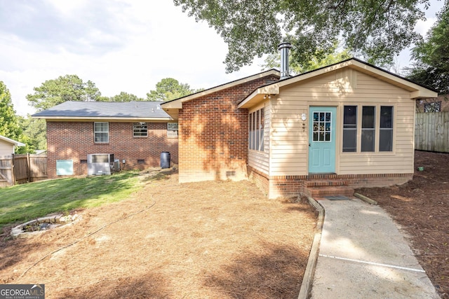 back of property with a lawn and central AC