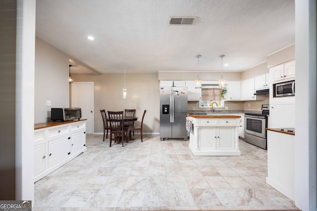 kitchen featuring sink, a textured ceiling, decorative light fixtures, white cabinets, and appliances with stainless steel finishes