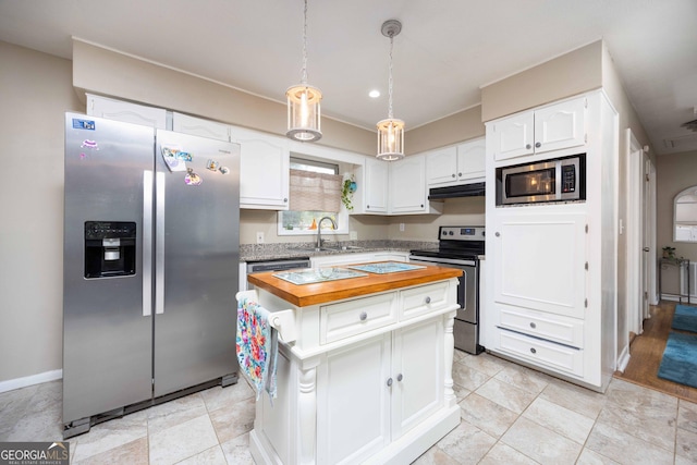 kitchen featuring wooden counters, appliances with stainless steel finishes, pendant lighting, white cabinets, and a kitchen island