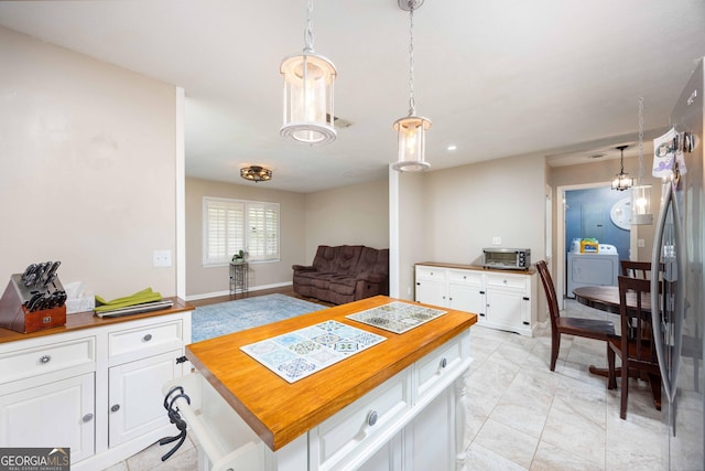 kitchen featuring butcher block counters, white cabinetry, a kitchen island, and hanging light fixtures