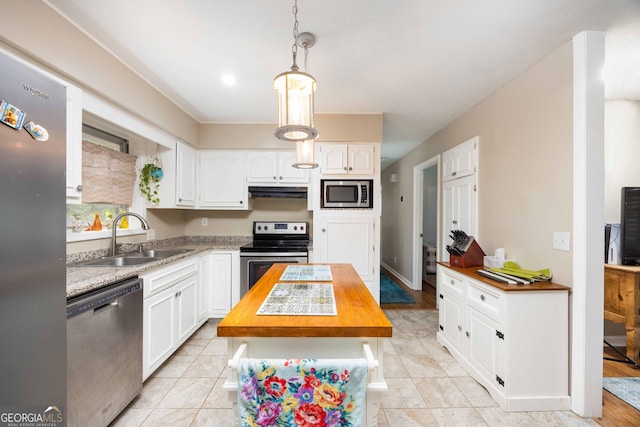 kitchen with a kitchen island, butcher block counters, stainless steel appliances, and white cabinetry