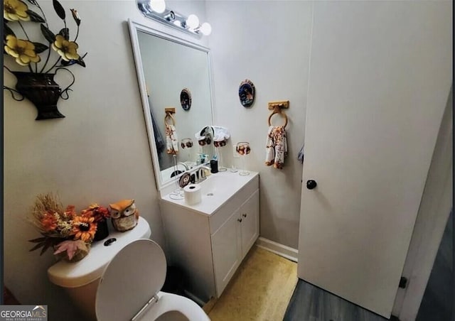 bathroom with wood-type flooring, toilet, and vanity