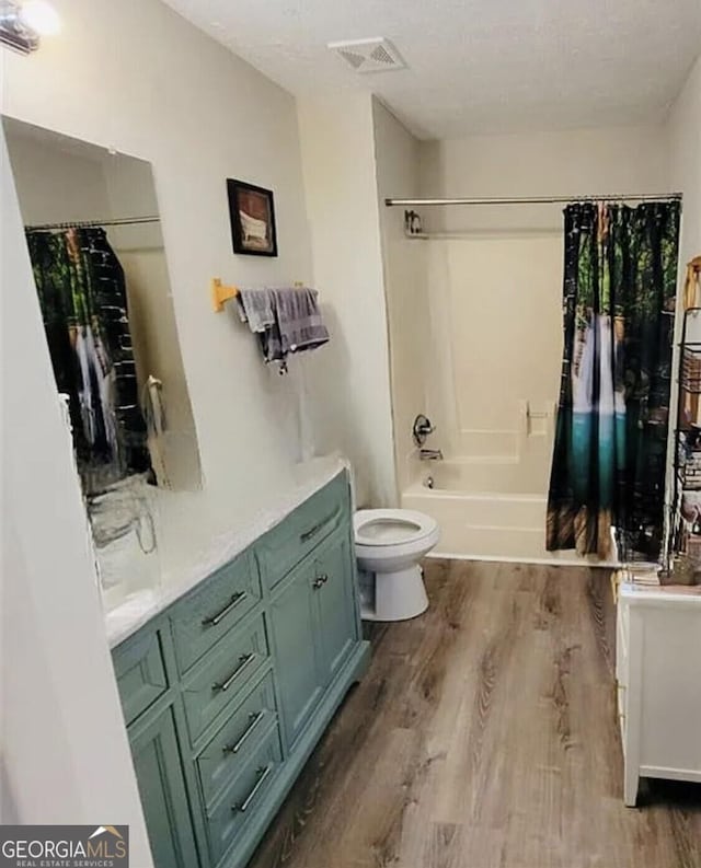 full bathroom with shower / bath combo with shower curtain, hardwood / wood-style flooring, toilet, and vanity