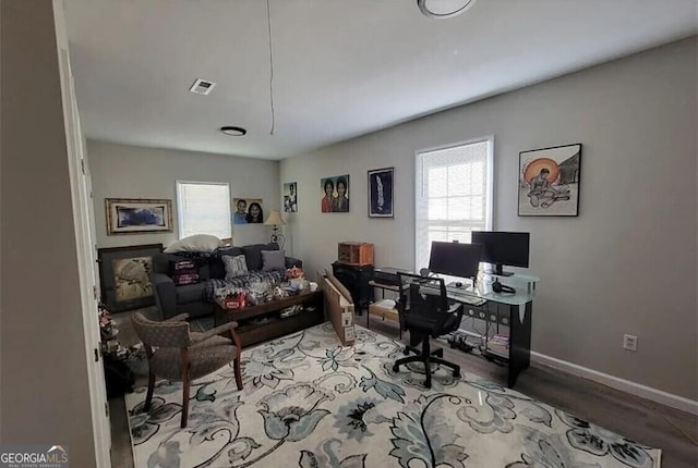 office with hardwood / wood-style floors and a healthy amount of sunlight