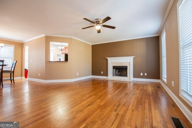 unfurnished living room featuring hardwood / wood-style flooring, ceiling fan with notable chandelier, a fireplace, and crown molding