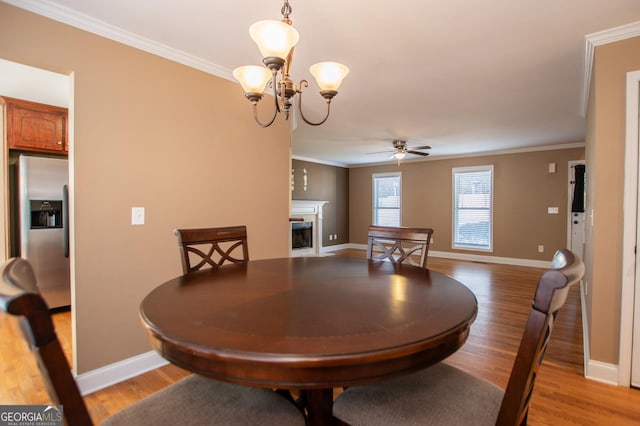 dining space featuring ceiling fan with notable chandelier, light hardwood / wood-style flooring, and crown molding