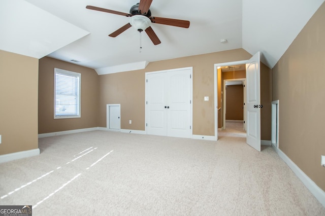 unfurnished bedroom featuring ceiling fan, a closet, light carpet, and vaulted ceiling