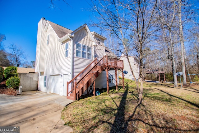 view of side of property featuring a yard, a garage, and a wooden deck