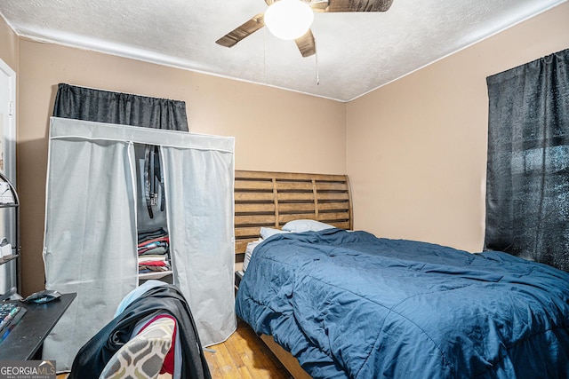 bedroom with ceiling fan, hardwood / wood-style floors, and a textured ceiling