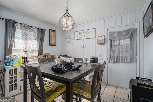 tiled dining space featuring crown molding, wood walls, a chandelier, and a textured ceiling