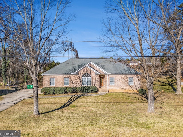view of front of home with a front lawn, a shingled roof, and brick siding