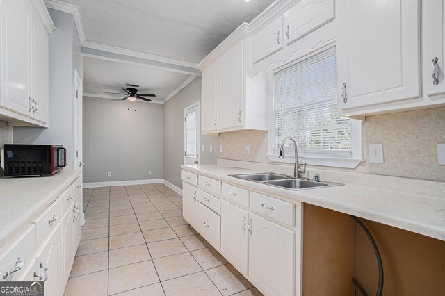 kitchen with white cabinetry, sink, a textured ceiling, light tile patterned floors, and ornamental molding