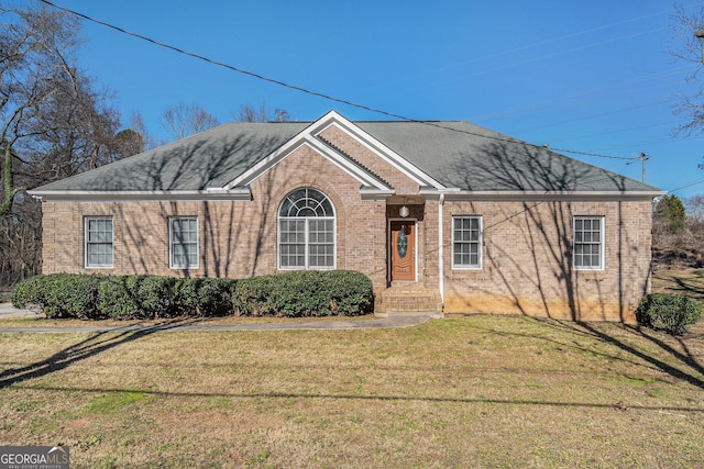 ranch-style house with a shingled roof, brick siding, and a front lawn