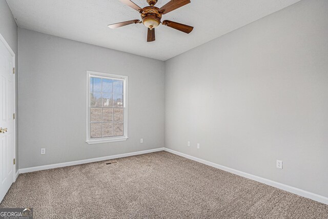 empty room with ceiling fan, carpet, and a textured ceiling