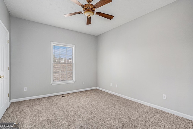 carpeted empty room with ceiling fan and baseboards