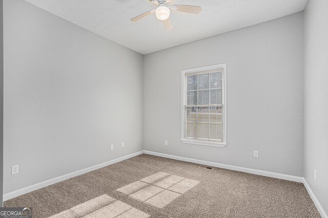 spare room with carpet flooring, ceiling fan, visible vents, and baseboards