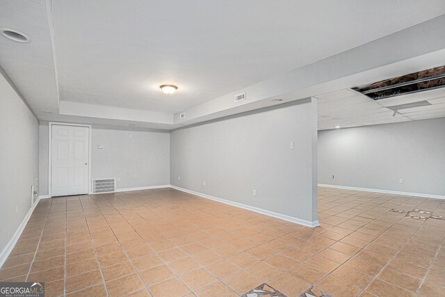 basement featuring a drop ceiling and light tile patterned flooring