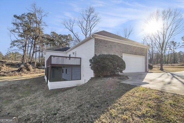 view of home's exterior with a garage, concrete driveway, brick siding, and a sunroom
