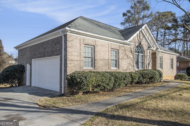 view of side of property with concrete driveway, brick siding, and an attached garage
