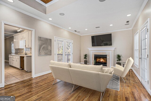 living room with a fireplace, light hardwood / wood-style flooring, and ornamental molding