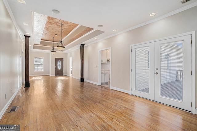 unfurnished living room with light wood-type flooring, a tray ceiling, french doors, and visible vents