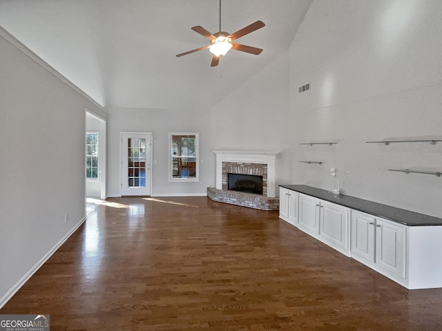 unfurnished living room featuring high vaulted ceiling, a brick fireplace, ceiling fan, and dark wood-type flooring