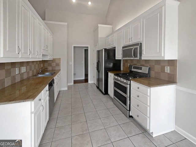 kitchen with white cabinetry, sink, light tile patterned flooring, and appliances with stainless steel finishes