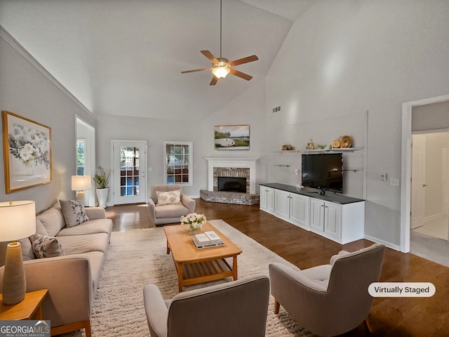 living room featuring hardwood / wood-style flooring, ceiling fan, high vaulted ceiling, and a brick fireplace