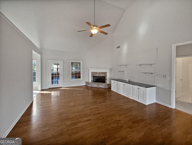 unfurnished living room with ceiling fan, a fireplace, high vaulted ceiling, and dark wood-type flooring