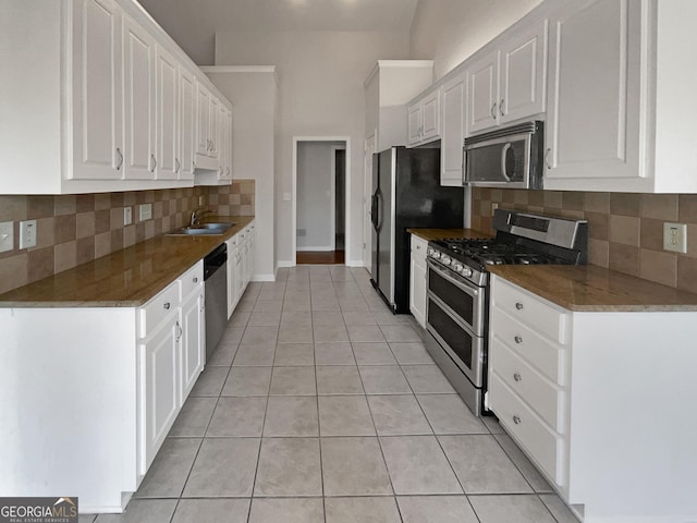 kitchen with white cabinets, appliances with stainless steel finishes, tasteful backsplash, and light tile patterned flooring