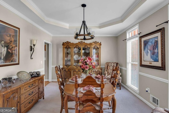 dining room featuring a chandelier, a tray ceiling, crown molding, and light colored carpet