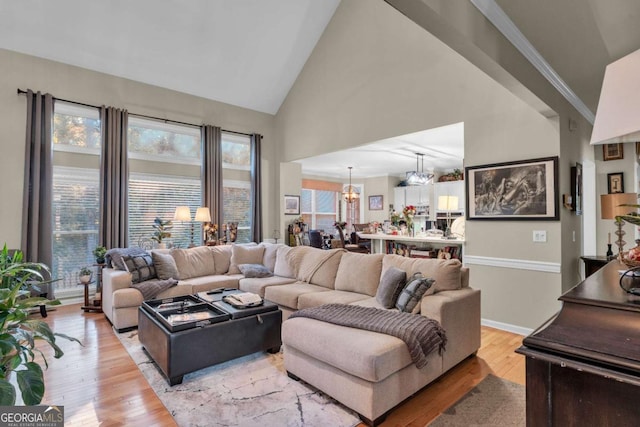 living room featuring light wood-type flooring, crown molding, a wealth of natural light, and a chandelier