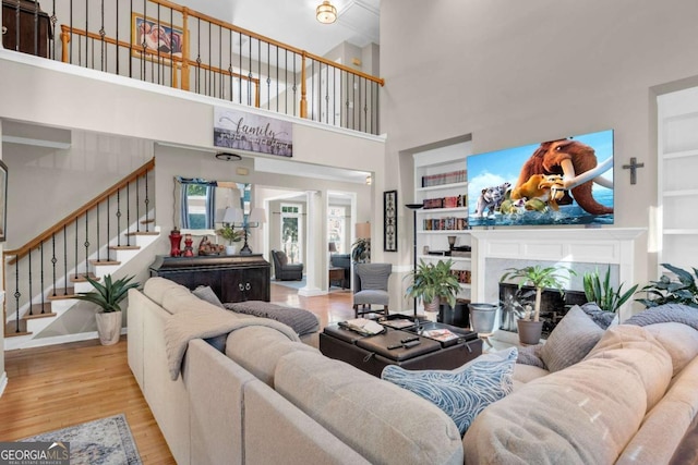 living room with a high ceiling, light hardwood / wood-style flooring, and built in features