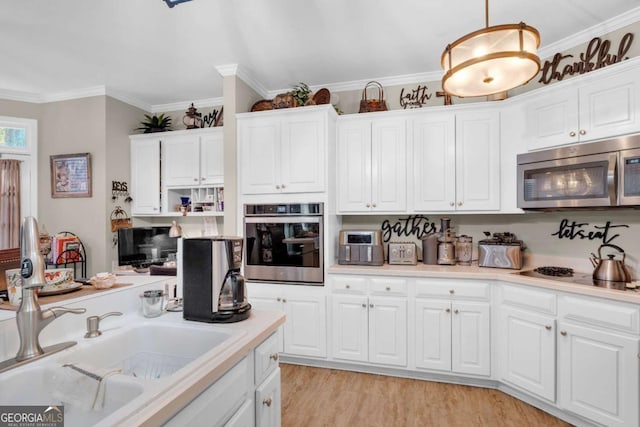 kitchen with sink, stainless steel appliances, crown molding, pendant lighting, and white cabinets