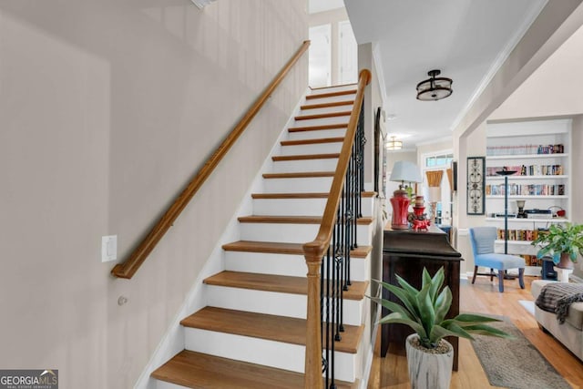 stairs with wood-type flooring and crown molding