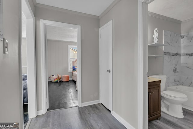 full bathroom featuring washtub / shower combination, toilet, crown molding, vanity, and hardwood / wood-style flooring