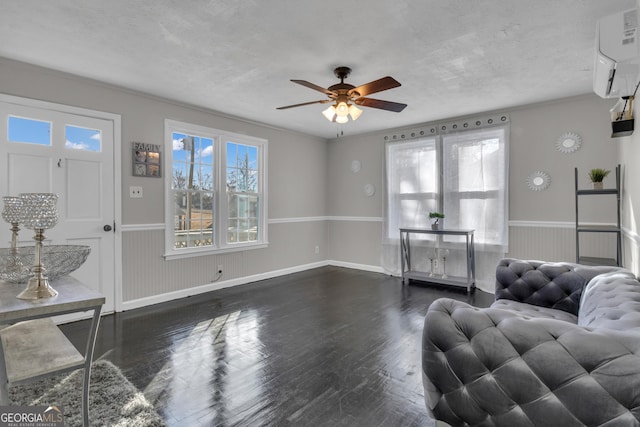 living room featuring a wall mounted air conditioner, dark wood-type flooring, a textured ceiling, and ceiling fan