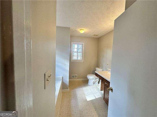 bathroom featuring vanity, toilet, a textured ceiling, and a tub