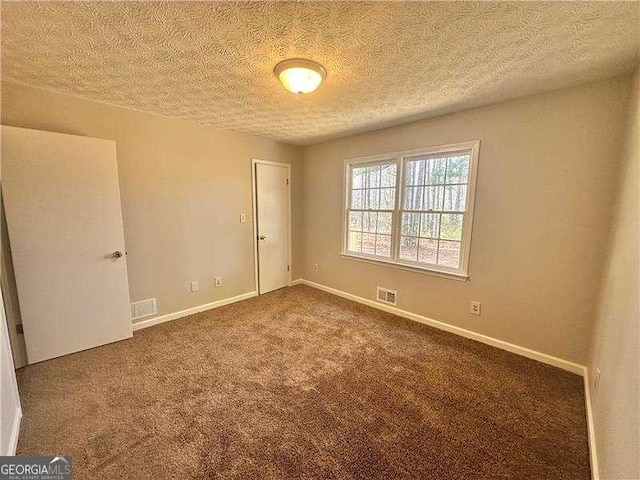 carpeted spare room with a textured ceiling