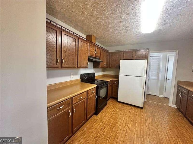 kitchen with white fridge, light wood-type flooring, a textured ceiling, and black range with electric cooktop