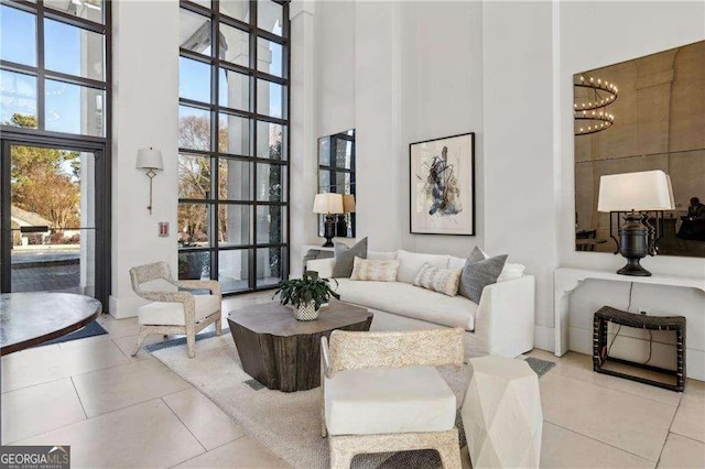 tiled living room featuring a notable chandelier and a high ceiling