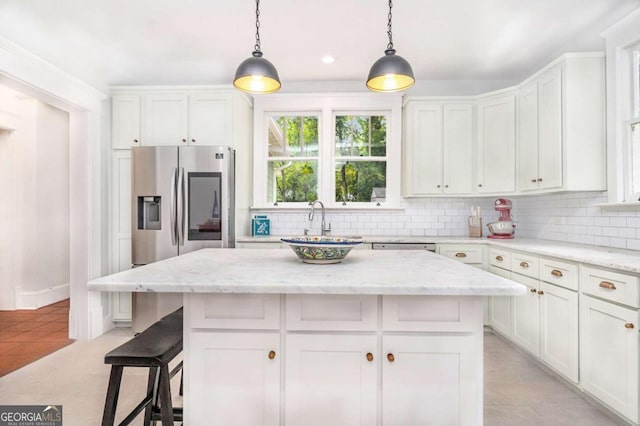 kitchen featuring light stone countertops, a center island, and white cabinets