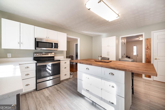 kitchen featuring wood counters, white cabinets, and appliances with stainless steel finishes