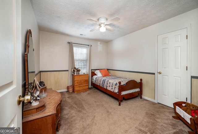 bedroom with carpet, ceiling fan, a textured ceiling, and wooden walls