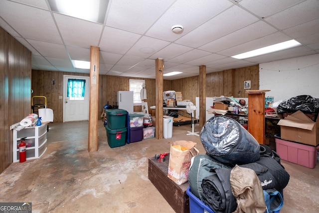 basement with a drop ceiling and wood walls